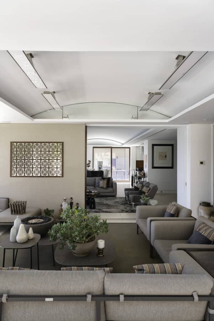 Spacious loung room with white and coffee toned furnishings and white heating on a curved ceiling