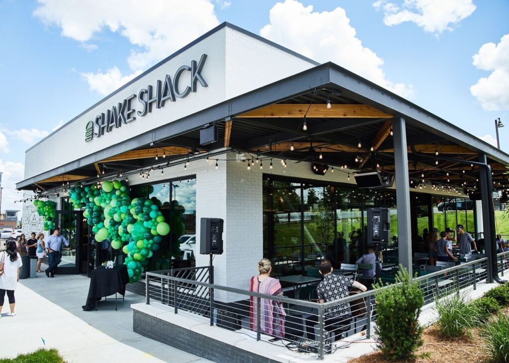 Shake Shack restaurant bustling with customers and hundreds of green balloons out front and Gas heaters