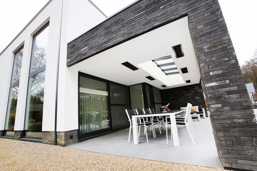 Grey and white modern outdoor alfresco area with featured black brickwork, sky roof and electric heaters