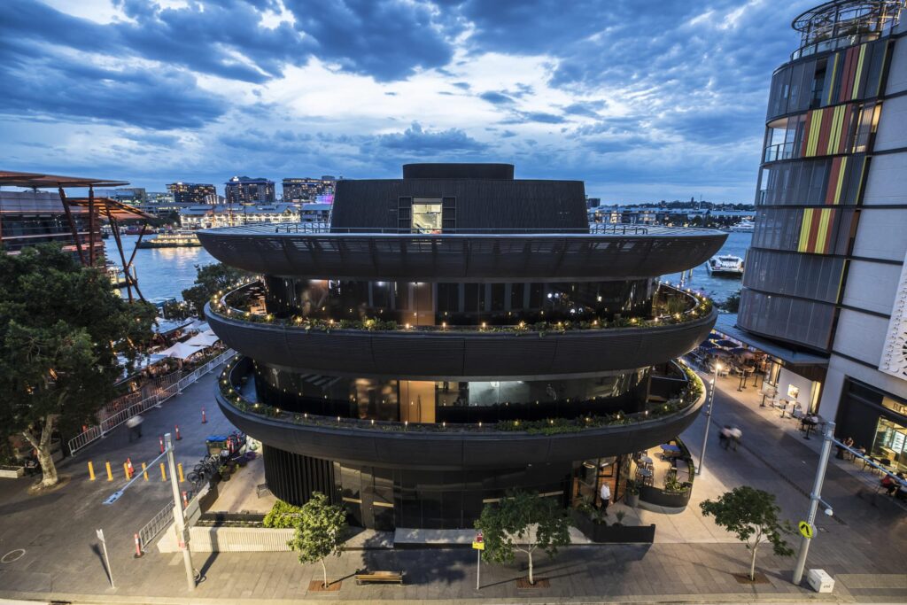 Wide view of four storey curved building at dusk