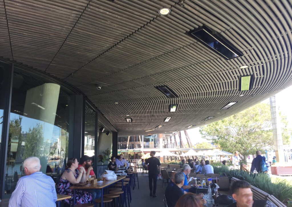 Extended awning with built-in heating above busy dining area